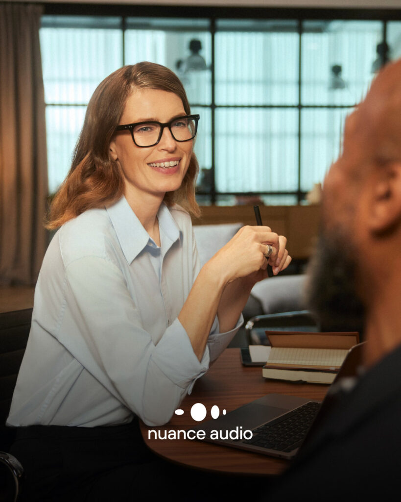Nuance Audio Brillen, die auch hören können. Frau sitzt im Meeting.